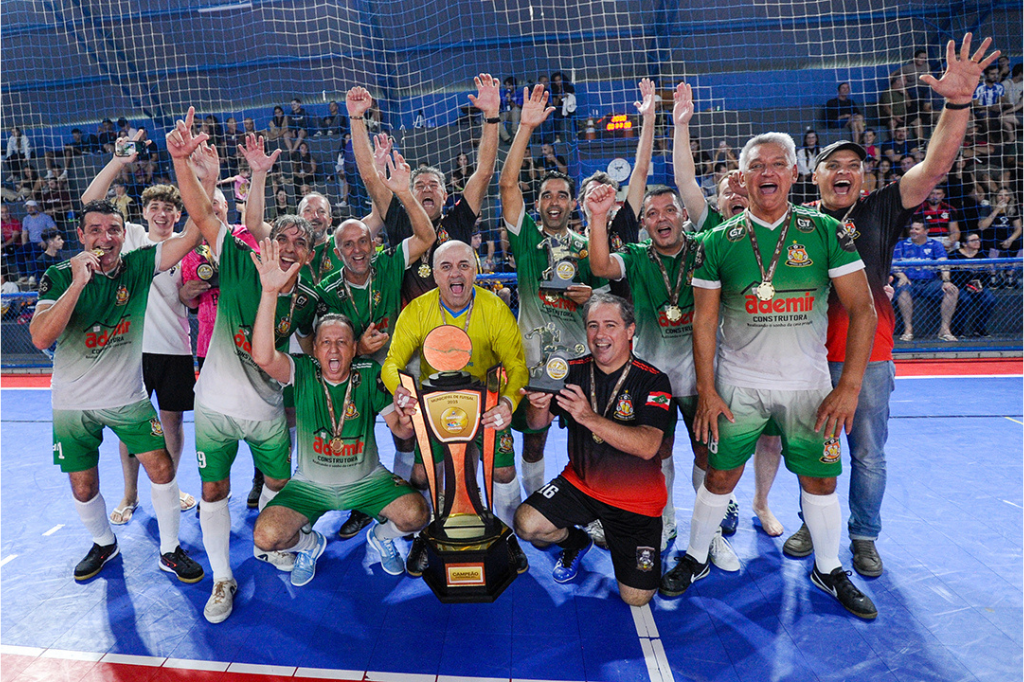 Foto: APMG/SETUR - Garopaba conhece seus campeões do Futsal Municipal em noite de grandes finais. Amigos de Quarta comemorando a conquista com seu troféu