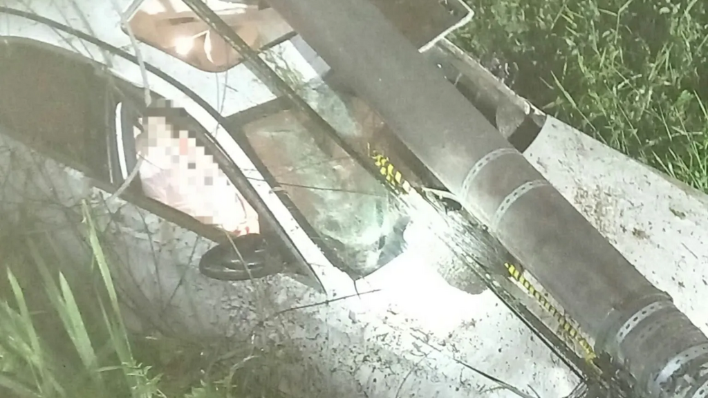 Carro sai da pista, cai em córrego e fica preso sob poste na SC-443