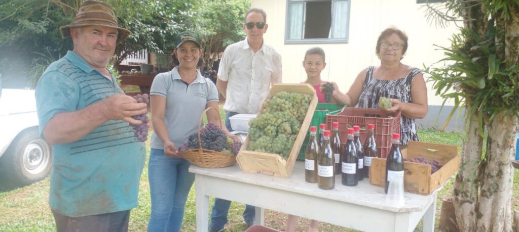  - Foto legenda: Shilon terceiro da esquerda para a direita, com parte da Famíliach e alguns produtos fornecidos com a referência mencionada propriedade rural.