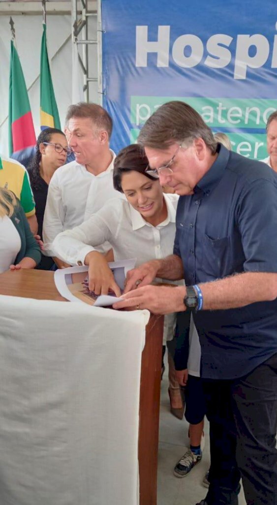 Divulgação - Michele e Bolsonaro olham atentos uma foto que ele recebeu,  de quanto ainda estava na escola do Exército