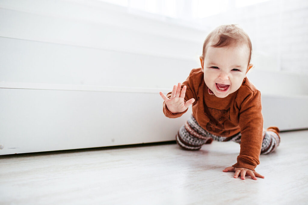  - Happy child in orange sweater plays with feather on the floor