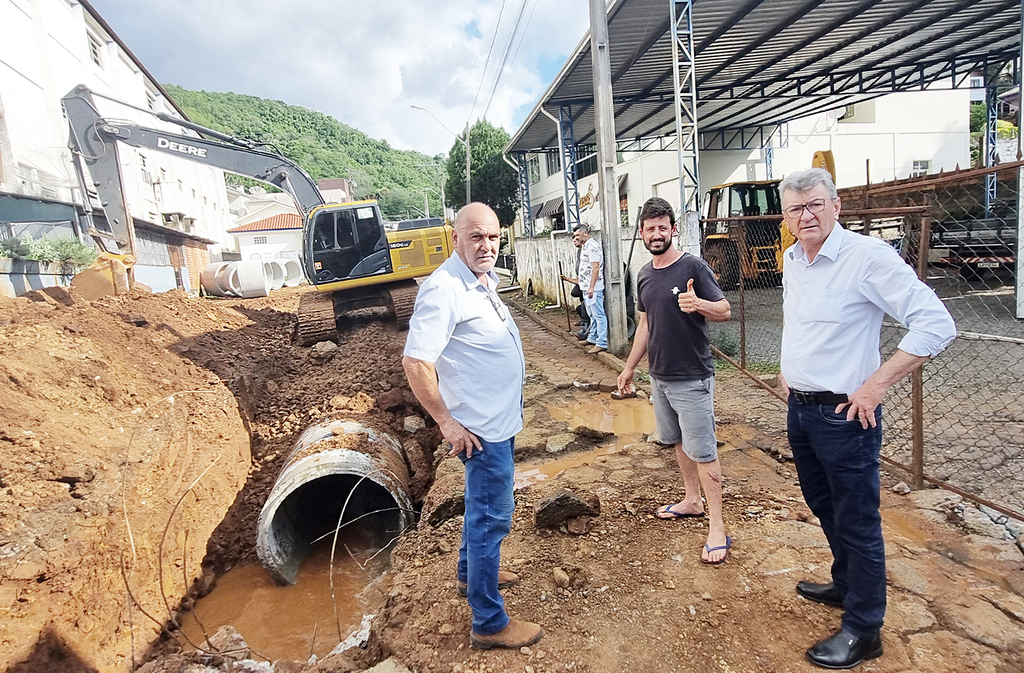 Aldo Azevedo / jornalista - Foto legenda: Secretário de Infraestrutura; Paulinho Ribeiro, morador e proprietário de imóvel por onde passa as águas no final da Rua José Cadorin (Jefferson Savaris) e o prefeito Dorini no momento em que a máquina da Prefeitura prestava serviços à municipalidade.