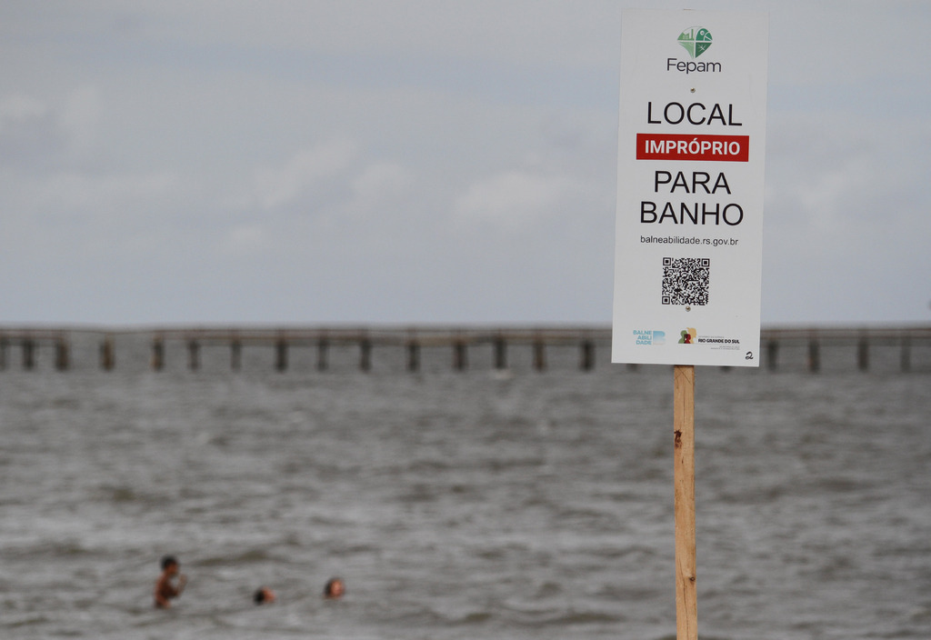 Foto: Carlos Queiroz - DP - Mesmo com a placa que sinaliza o local como inadequado, diversos veranistas seguem entrando na água