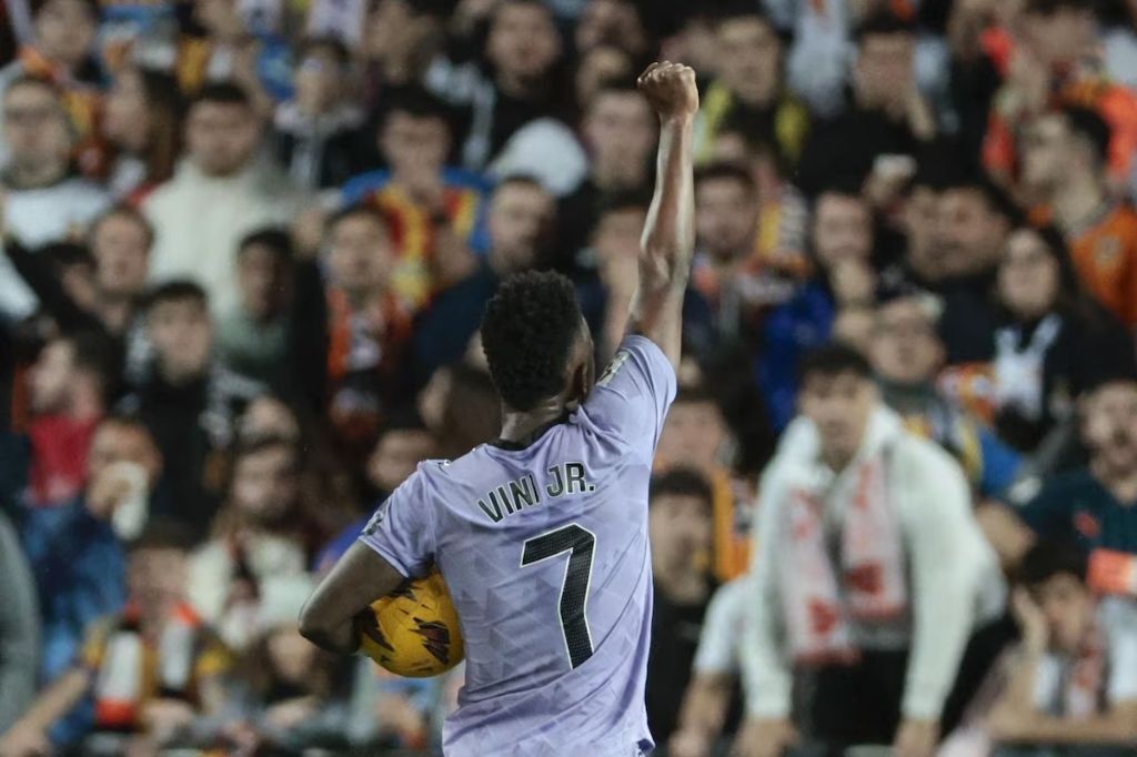  - Foto: Vinícius Júnior celebando gol contra o Valencia com o punho cerrado e olhando para a torcida adversária. Foto: Biel Aliño./EFE